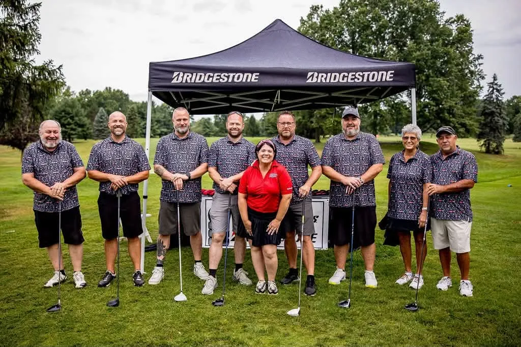 A team posing under a tent at the golf outing